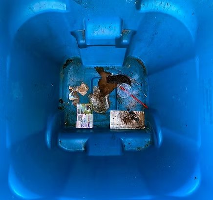 Inside of a blue bin before cleaning — debris and stuck-on waste