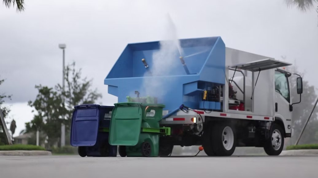 The BluWave rig mid-wash — two bins on the lift, 200-degree steam rising
